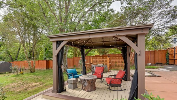 A covered patio area with outdoor furniture, including chairs and a table.