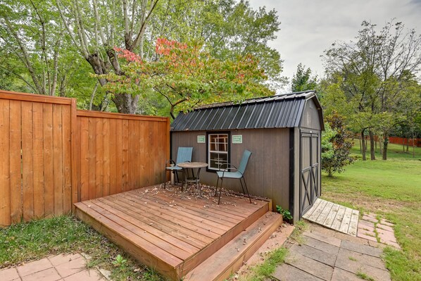 A wooden deck with a table and chairs, a shed with a metal roof, and a wooden fence.