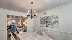 Un espace repas avec une table en marbre, des chaises blanches et un lustre.