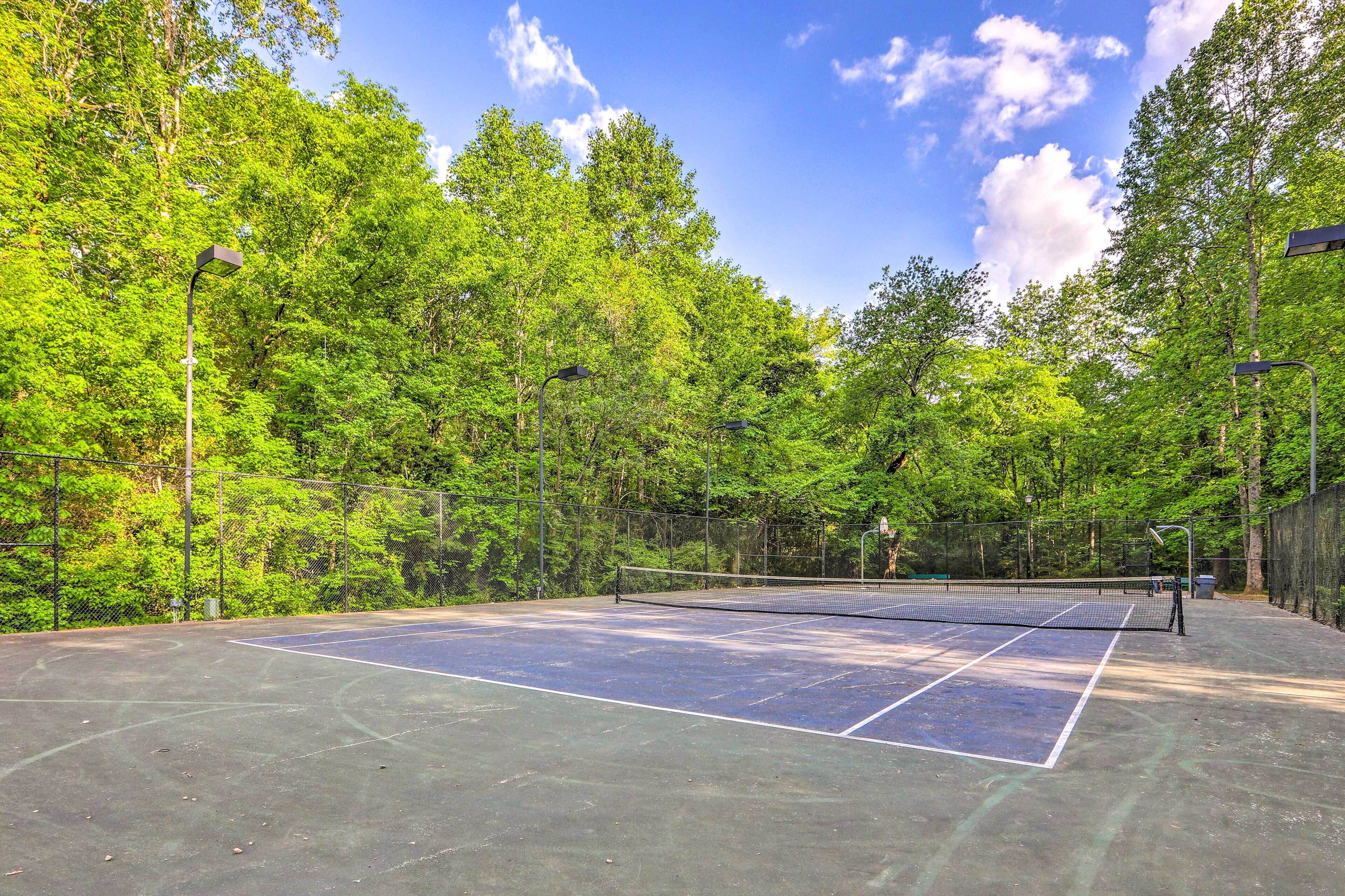 Una cancha de tenis al aire libre rodeada de árboles.