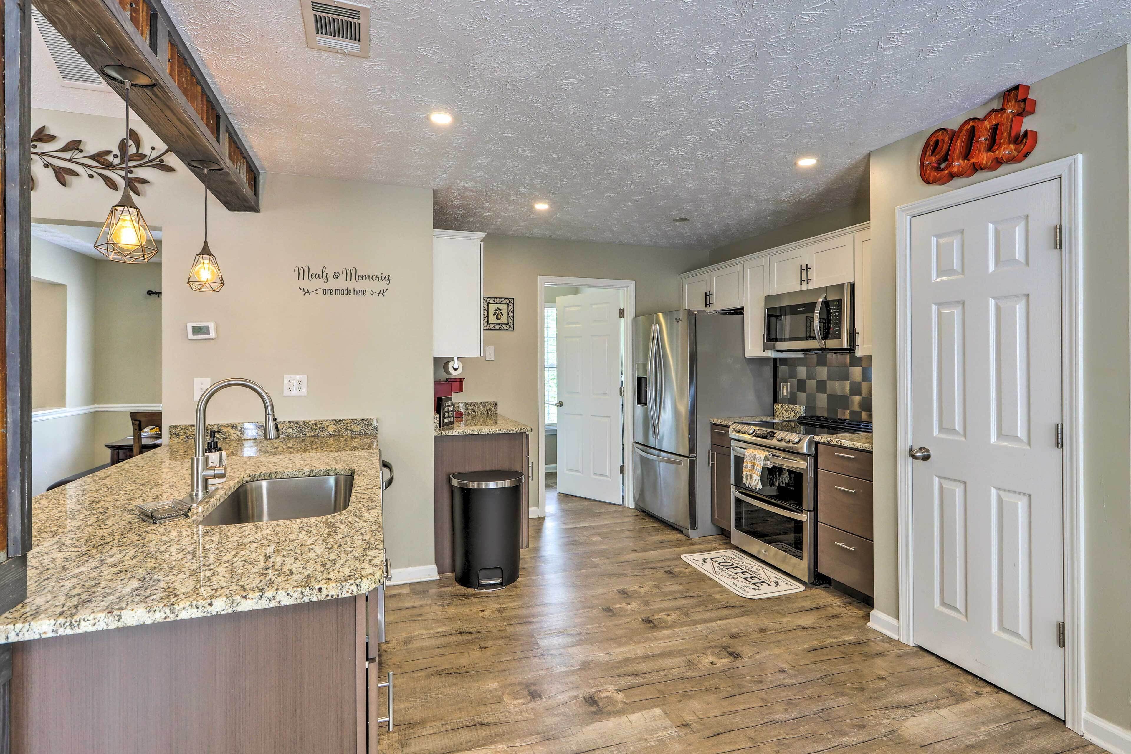 A kitchen with granite countertops, stainless steel appliances, and a wooden floor.