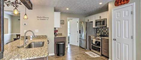 A kitchen with granite countertops, stainless steel appliances, and a wooden floor.