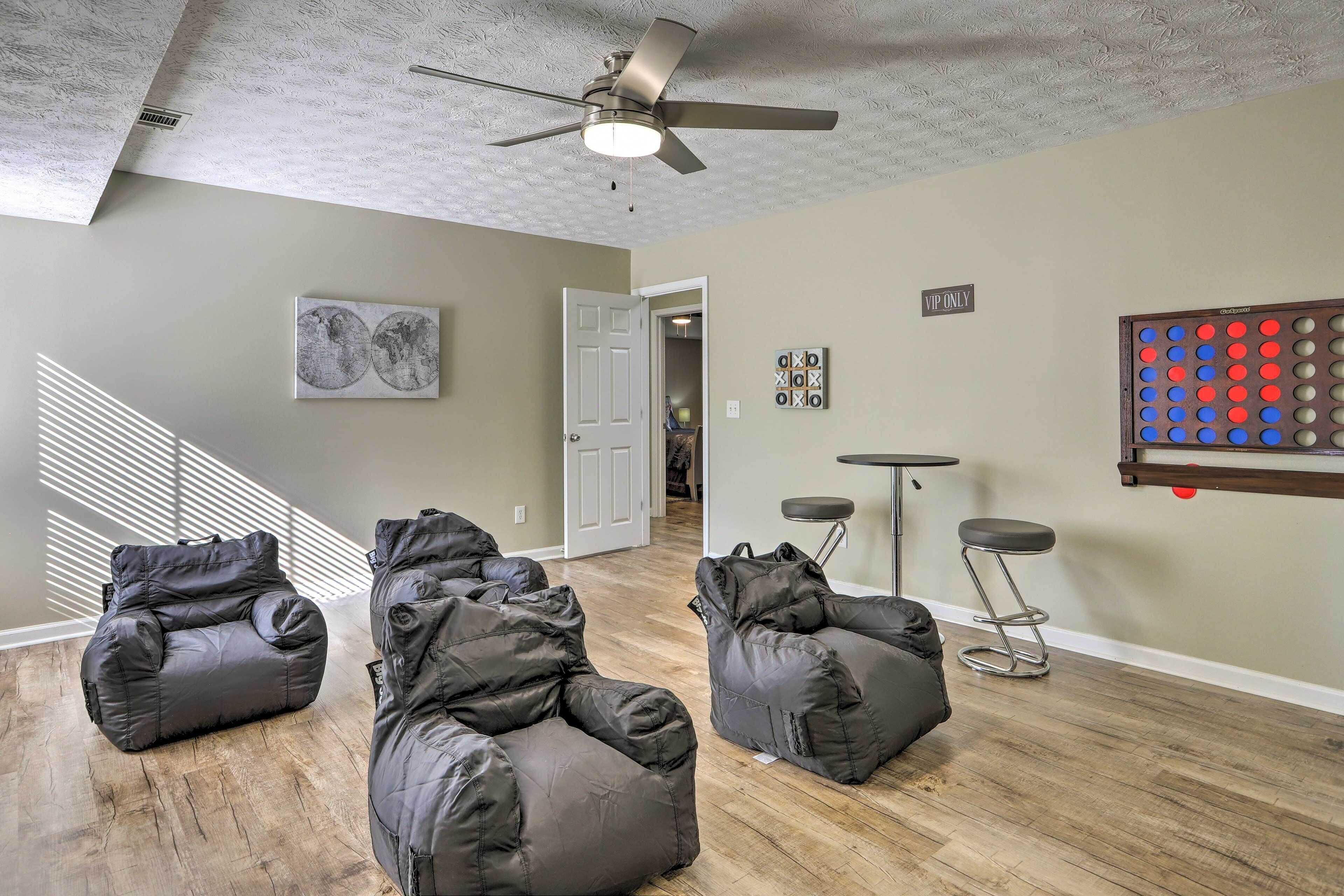 Ein Zimmer mit Deckenventilator, einer Tür, einem Bild, einem an der Wand befestigten Gesellschaftsspiel und drei Sitzsäcken.
