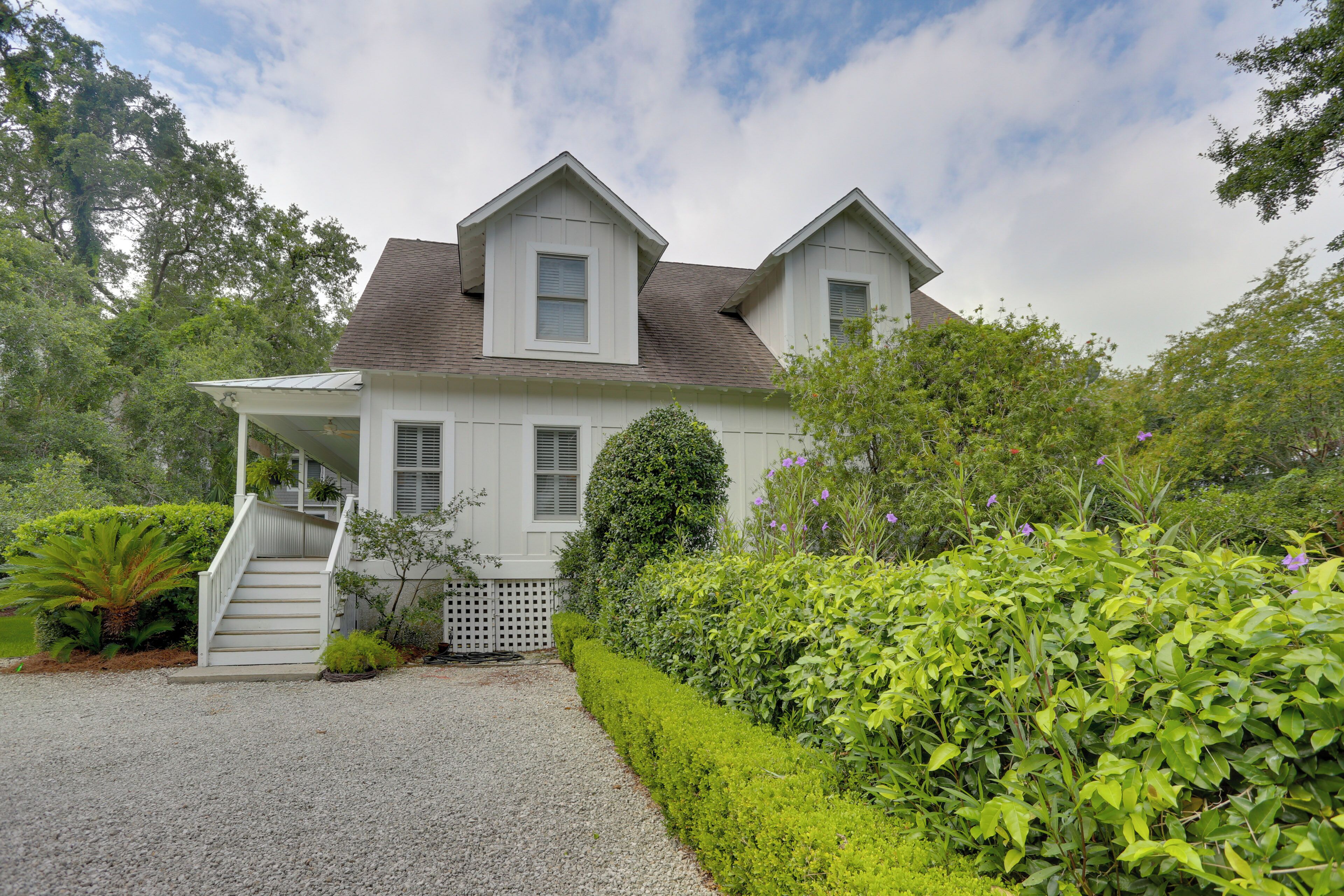 A two-story house with a covered porch, a gravel driveway, and well-maintained greenery.