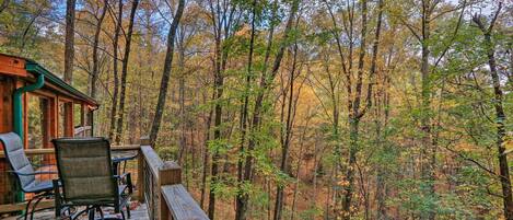 A wooden deck with outdoor seating and a view of a forest.