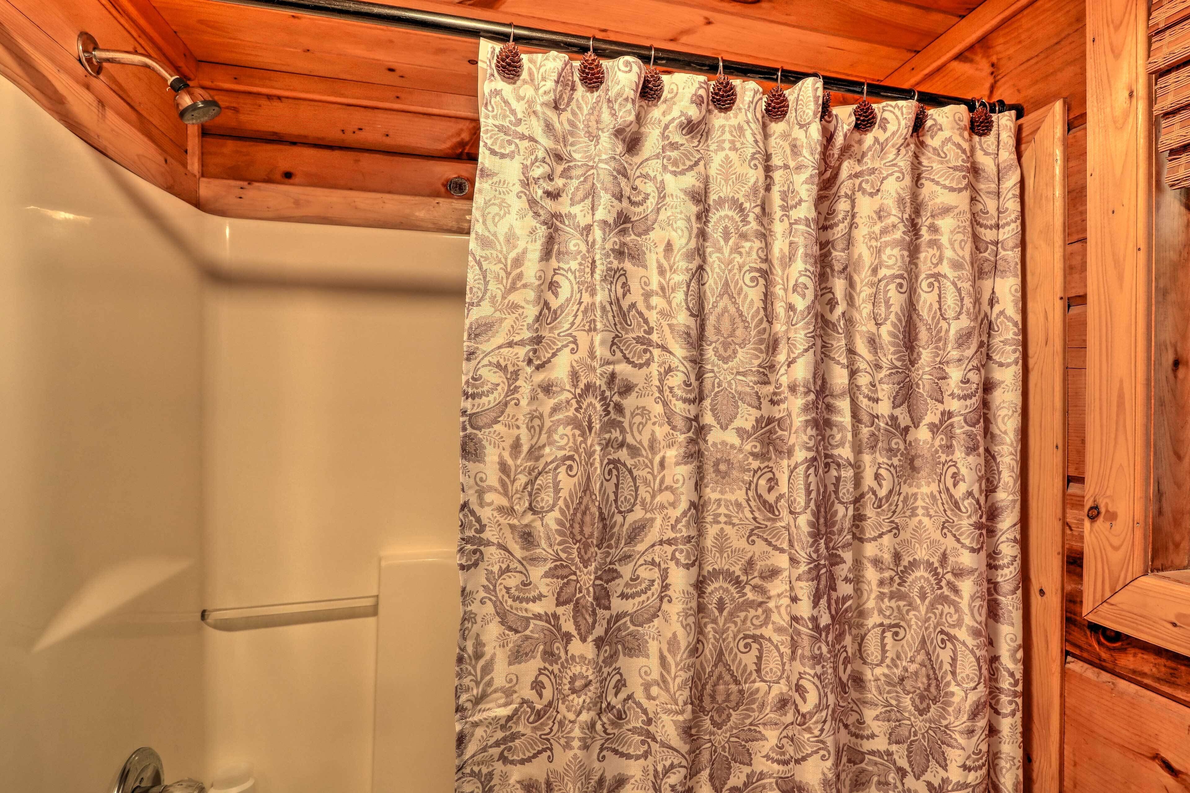Un baño con cortina de ducha estampada con motivos paisley y adornos de piñas.