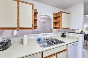 A modern kitchen with white cabinets, a stainless steel sink, a toaster, and a dishwasher.