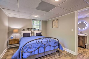 A bedroom with a bed, a nightstand, a window, and a bathroom with a sink and mirror. - 21 Mi to Atlanta: Getaway w/ Fire Pit! (Jonesboro)