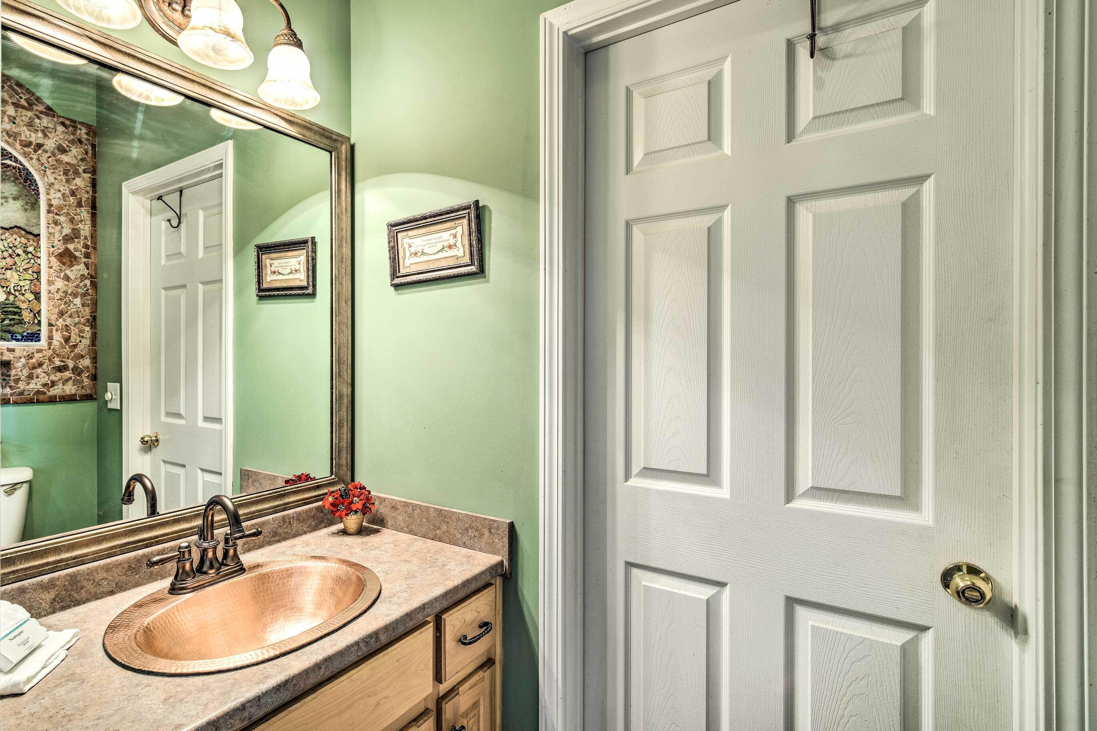 A bathroom with a sink, mirror, and a door.