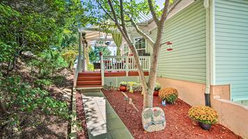 A house with a covered porch, a small garden with potted plants, and a pathway leading to the entrance.