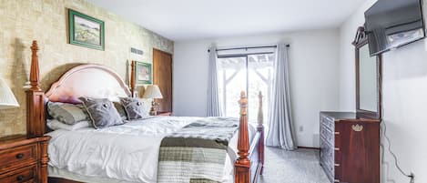 A bedroom with a wooden bed, a dresser, and a television.