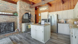 A kitchen with white cabinets, a brick fireplace, and a wooden ceiling. - Lawrenceville Gem w/ Boat Dock on Private Lake! (Lawrenceville)