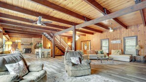 A spacious living area with wooden beams, a fireplace, and a staircase leading to another level. - Lawrenceville Gem w/ Boat Dock on Private Lake! (Lawrenceville)