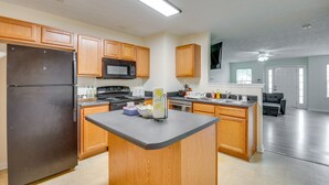 A modern kitchen with wooden cabinets, a stainless steel refrigerator, a microwave, and a central island. - Bright Decatur Townhome ~ 10 Mi to Atlanta! (Decatur)