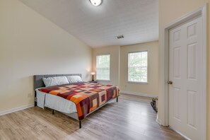 A bedroom with a bed, a nightstand, a lamp, and a door. - Bright Decatur Townhome ~ 10 Mi to Atlanta! (Decatur)