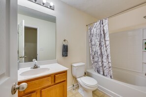 A bathroom with a white sink, wooden vanity, a toilet, and a bathtub with a marble-patterned shower curtain. - Bright Decatur Townhome ~ 10 Mi to Atlanta! (Decatur)