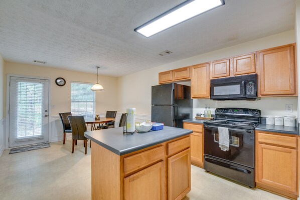 A kitchen with wooden cabinets, a black refrigerator, a microwave, and a stove. - Bright Decatur Townhome ~ 10 Mi to Atlanta! (Decatur)