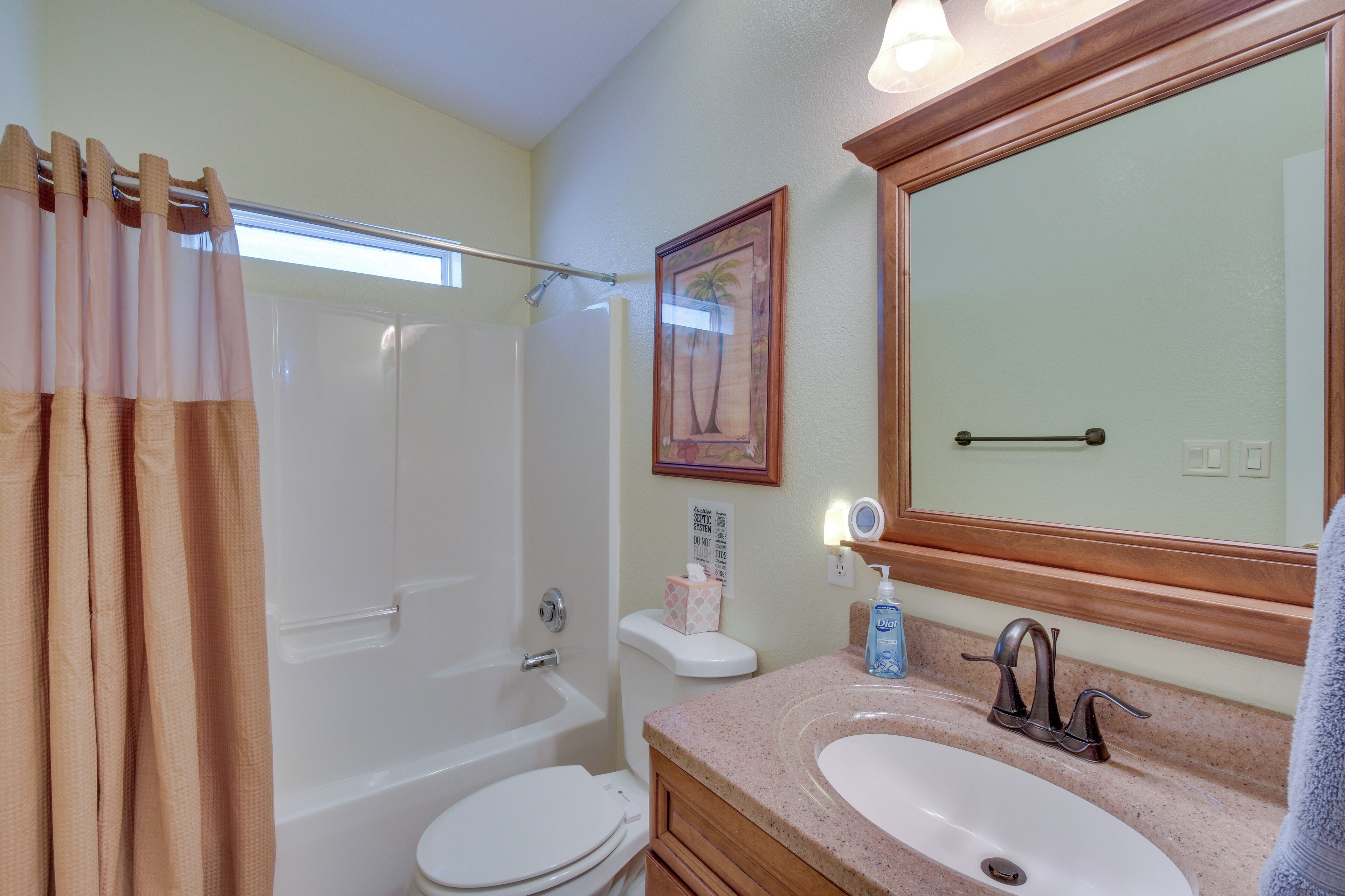 A bathroom with a bathtub, toilet, sink, and a large mirror.