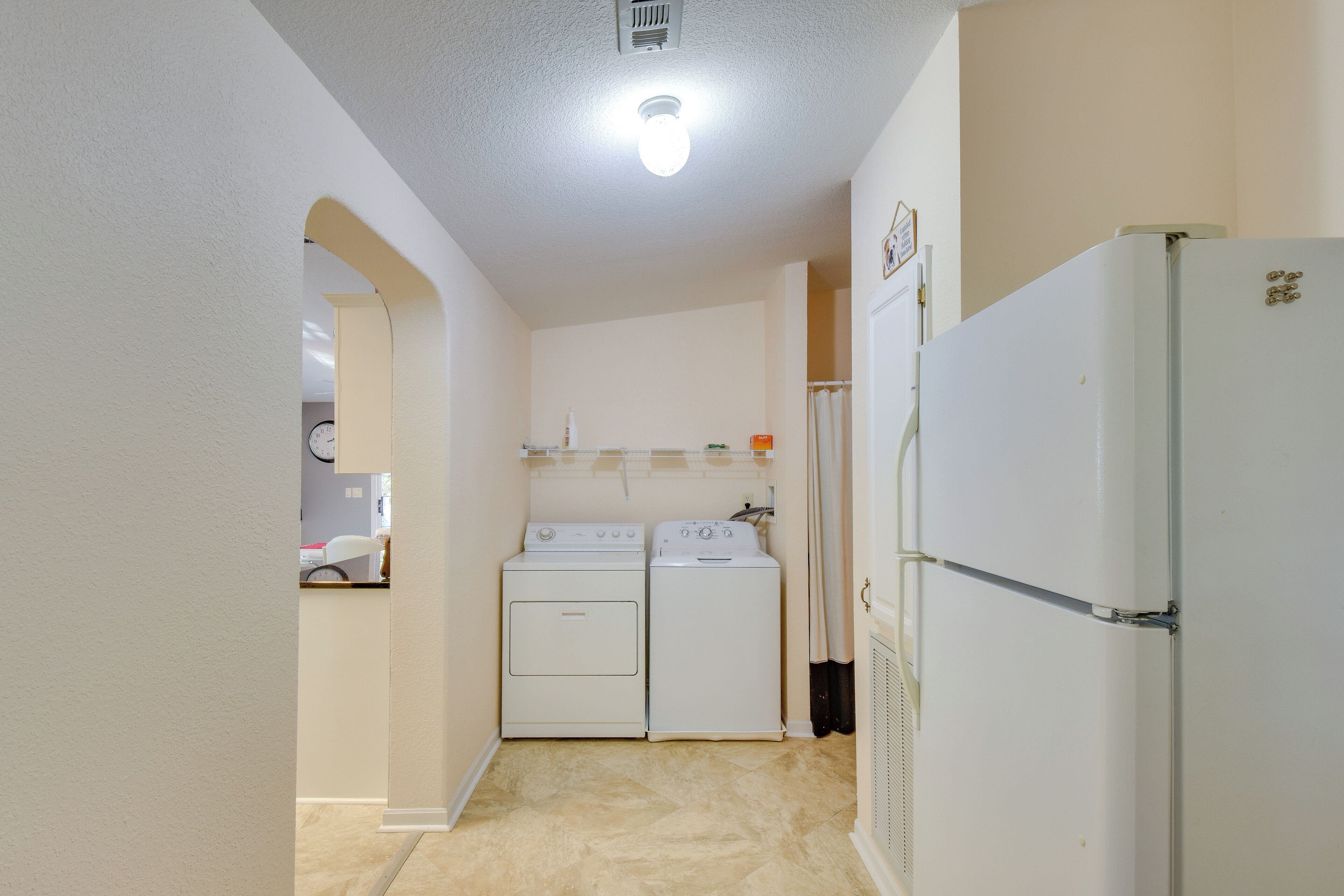A compact kitchen with a refrigerator, a washing machine, and a dryer.