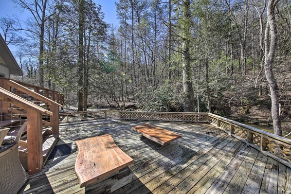 Een houten terras met picknicktafels, omringd door bebossing.