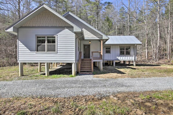 A two-story house with a front porch and a small attached structure. - Airy Ellijay Home w/ Spacious Creekside Deck! (Ellijay)