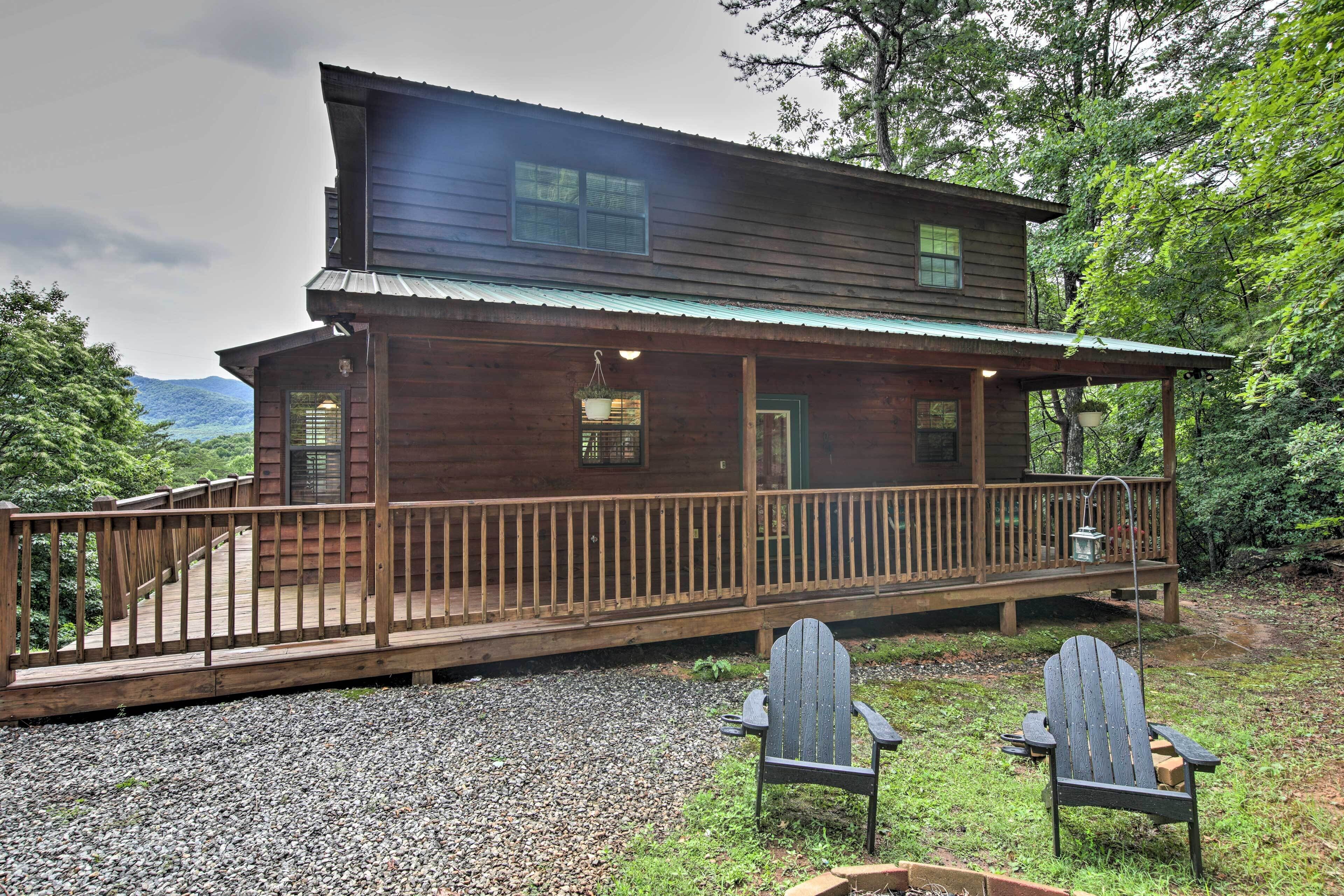 A wooden cabin with a deck and two Adirondack chairs.