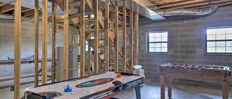 A room with exposed wooden beams, a foosball table, and a pool table.