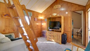 Ein Holzblock-Interieur mit Fernseher, einer Holztreppe und einem Schild, das Gäste willkommen heißt.