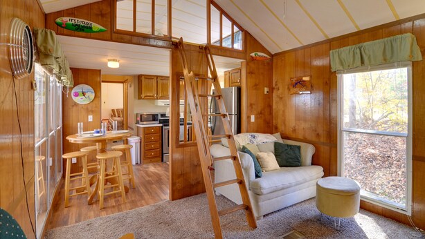 Ein Ferienhaus-Innenraum mit Essbereich, Küche und Schlafzimmer im oberen Bereich, erreichbar über eine Leiter.
