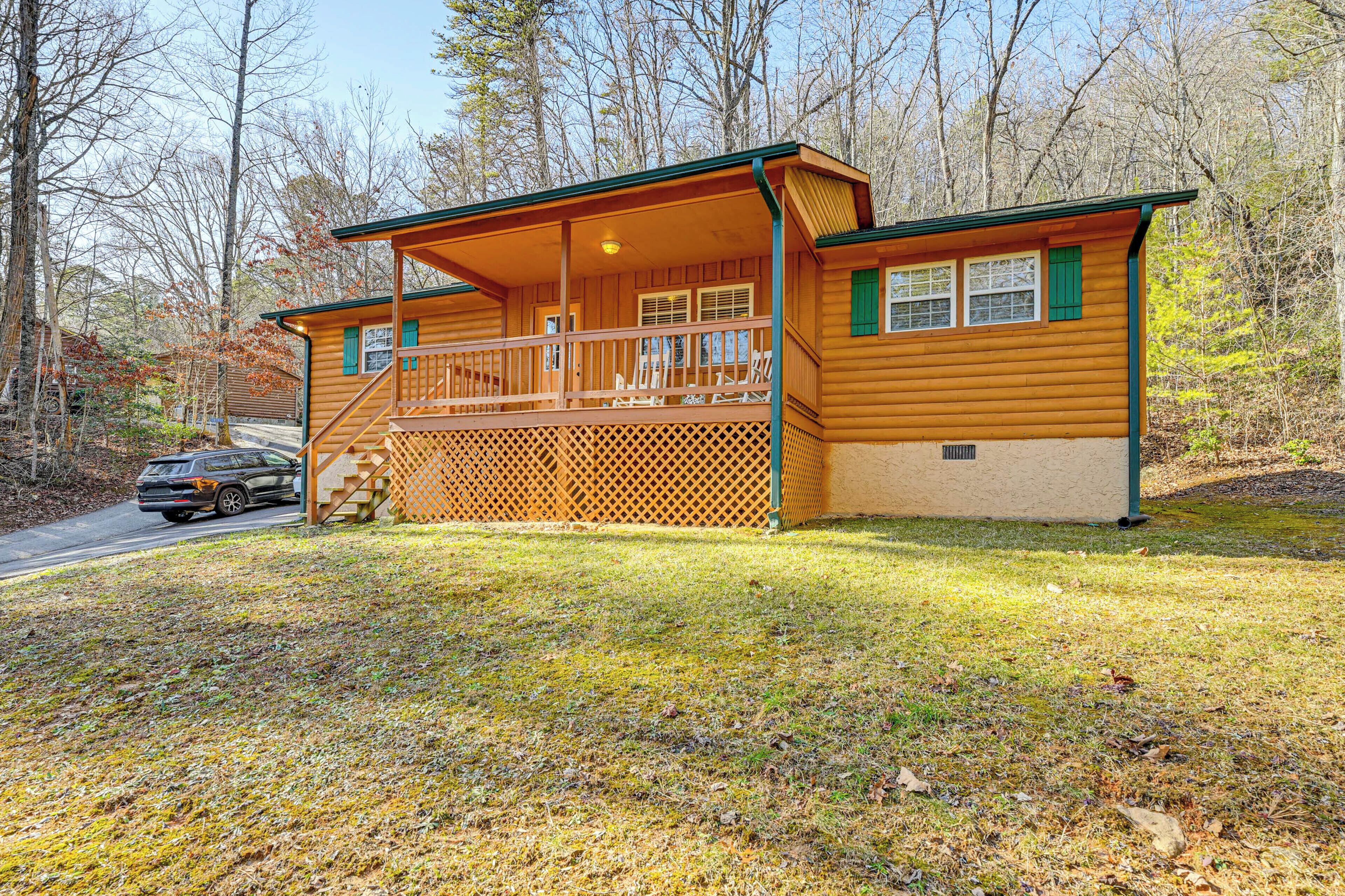 A log cabin with a porch, a covered deck, and a small front yard.