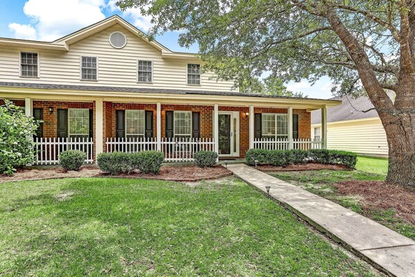 A two-story house with a front porch, brick facade, and a large tree in the yard. - Soothing Savannah Townhome With Patio! (Savannah)