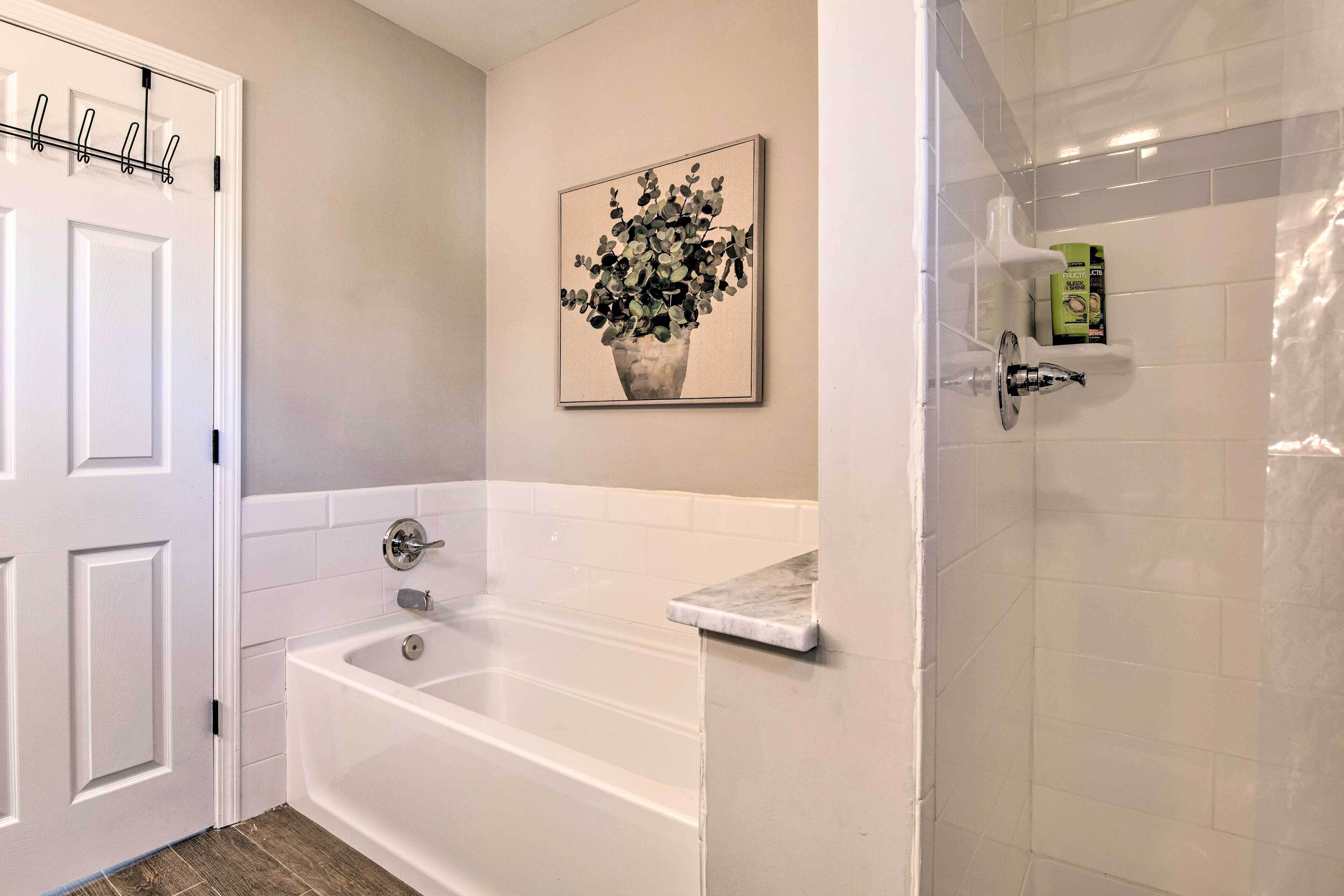 A bathroom with a white bathtub, a shower area, and a door with a coat rack.