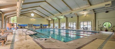 An indoor swimming pool with clear lanes, a diving board, and lounge chairs.