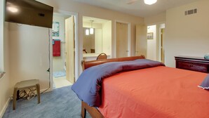 A bedroom with a bed, a ceiling fan, a TV, and a small stool.