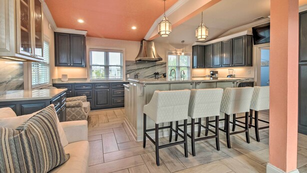 A modern kitchen with dark cabinets, a marble island, and bar stools.
