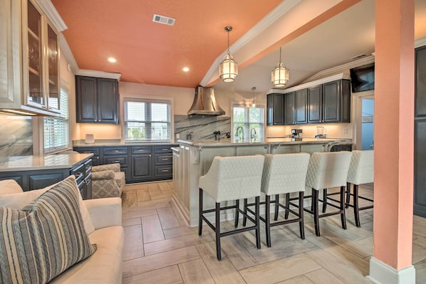 A modern kitchen with dark cabinets, a marble island, and bar stools. - Tybee Island Home w/ Rooftop & Ocean Views! (Tybee Island)