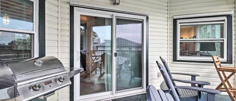 A covered patio area with a grill, sliding glass doors, and outdoor seating.