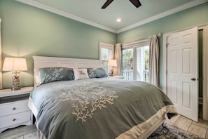 A bedroom with a large bed, a nightstand, a lamp, and a door to a balcony. - Tybee Island Home w/ Rooftop & Ocean Views! (Tybee Island)