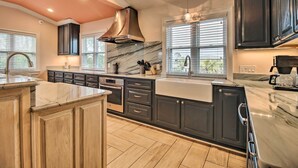 A modern kitchen with dark cabinetry, a marble countertop, and a stainless steel range hood.