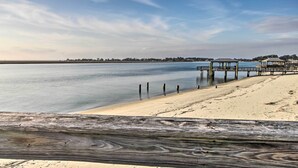A beach with a wooden walkway leading to a pier with structures.