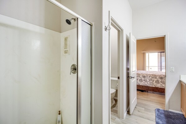 A bedroom with a bed, a window, and a bathroom with a shower. - Tucson Condo Rental w/ Balcony + Mountain View! (Tucson)