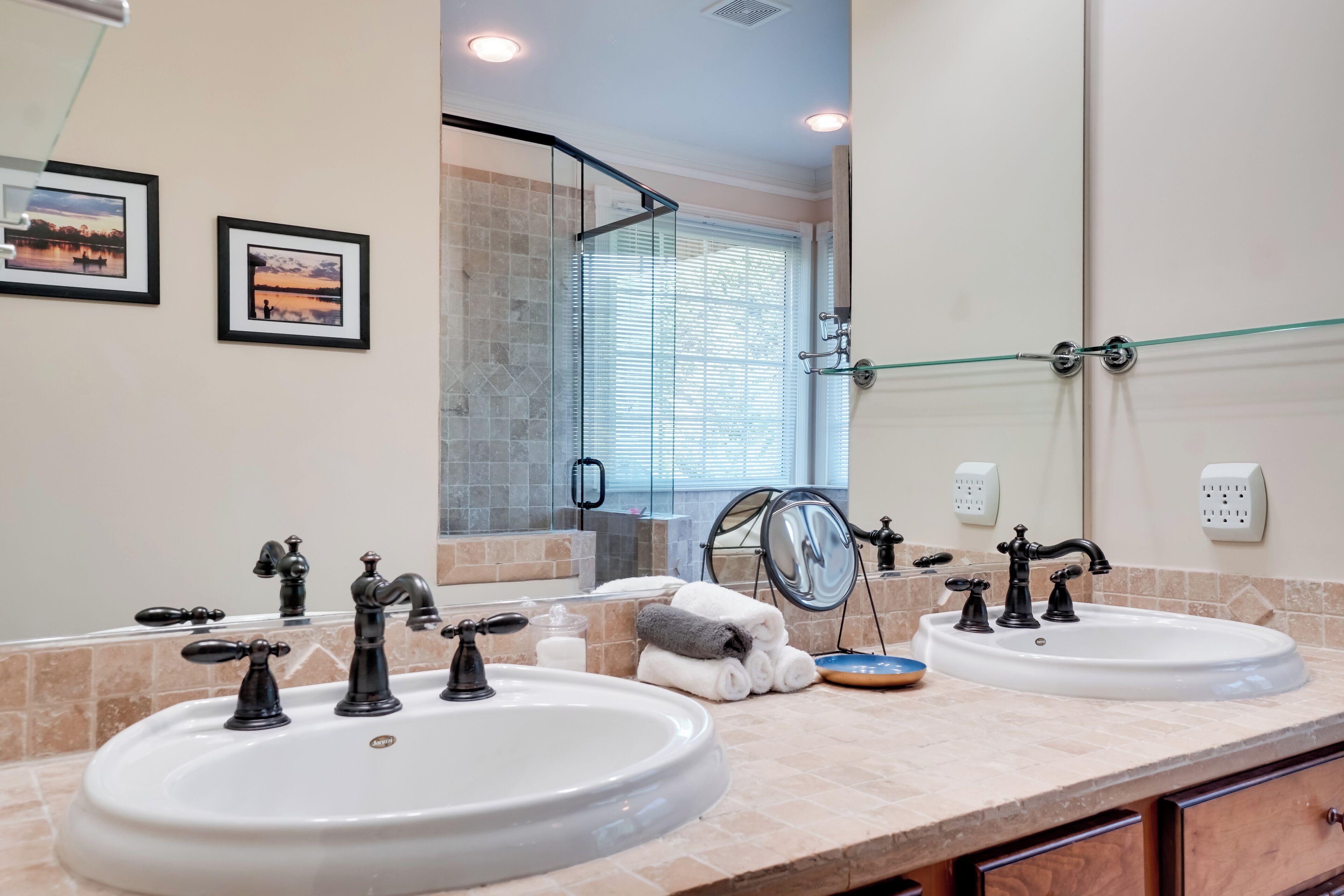 A bathroom with two sinks, a glass shower enclosure, and a large mirror.