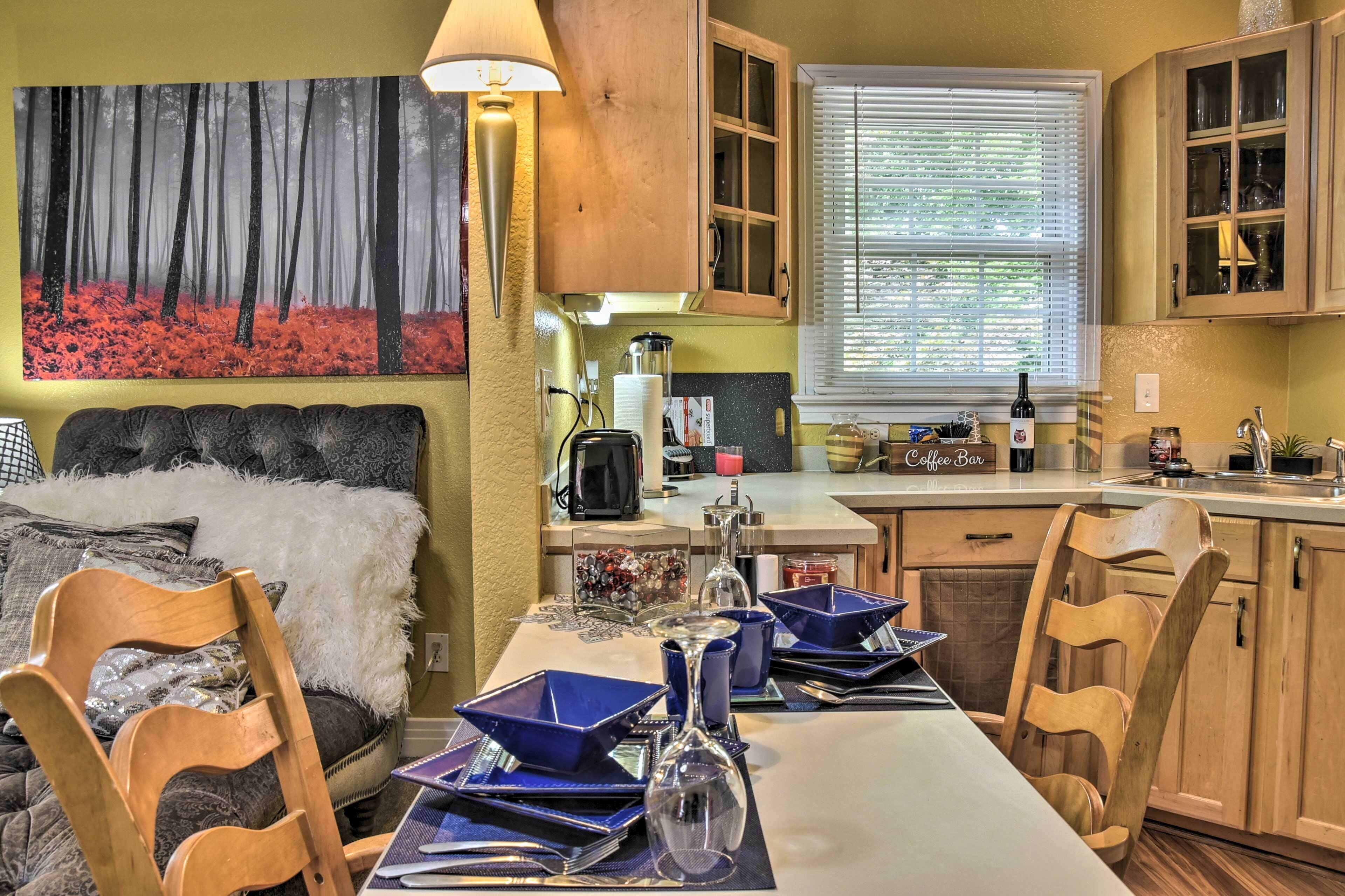 A compact kitchen with a dining area, a coffee bar, and a window with blinds.