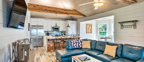 A spacious living area with a blue leather sofa, a wooden coffee table, and a ceiling fan.