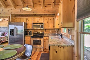 Compact kitchen with appliances, granite countertop, and sink, offering a functional cooking space with a scenic view.
