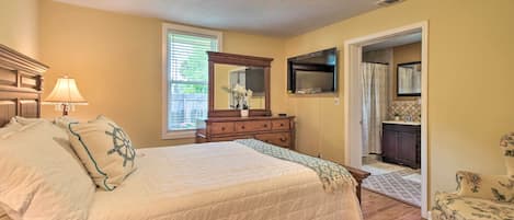 Un dormitorio con cama, cómoda, espejo y una silla.