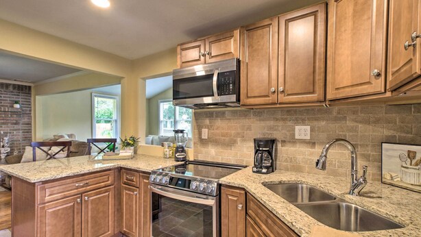 A kitchen with wooden cabinets, granite countertops, a stainless steel sink, a built-in oven, and a microwave. - Updated Savannah Hideaway w/ Luxury Backyard! (Savannah)