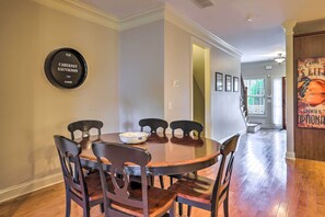 A dining area with a round table and six chairs, a wall-mounted wine cooler, and a staircase leading to another room. - Charming Lake Oconee Retreat - Steps to Lake! (Eatonton)