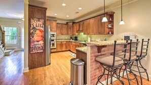 A modern kitchen with wooden cabinets, a granite countertop, and a brick island with bar stools. - Charming Lake Oconee Retreat - Steps to Lake! (Eatonton)