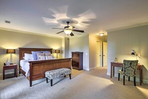 A bedroom with a wooden bed, a ceiling fan, a desk, and a chair. - Charming Lake Oconee Retreat - Steps to Lake! (Eatonton)